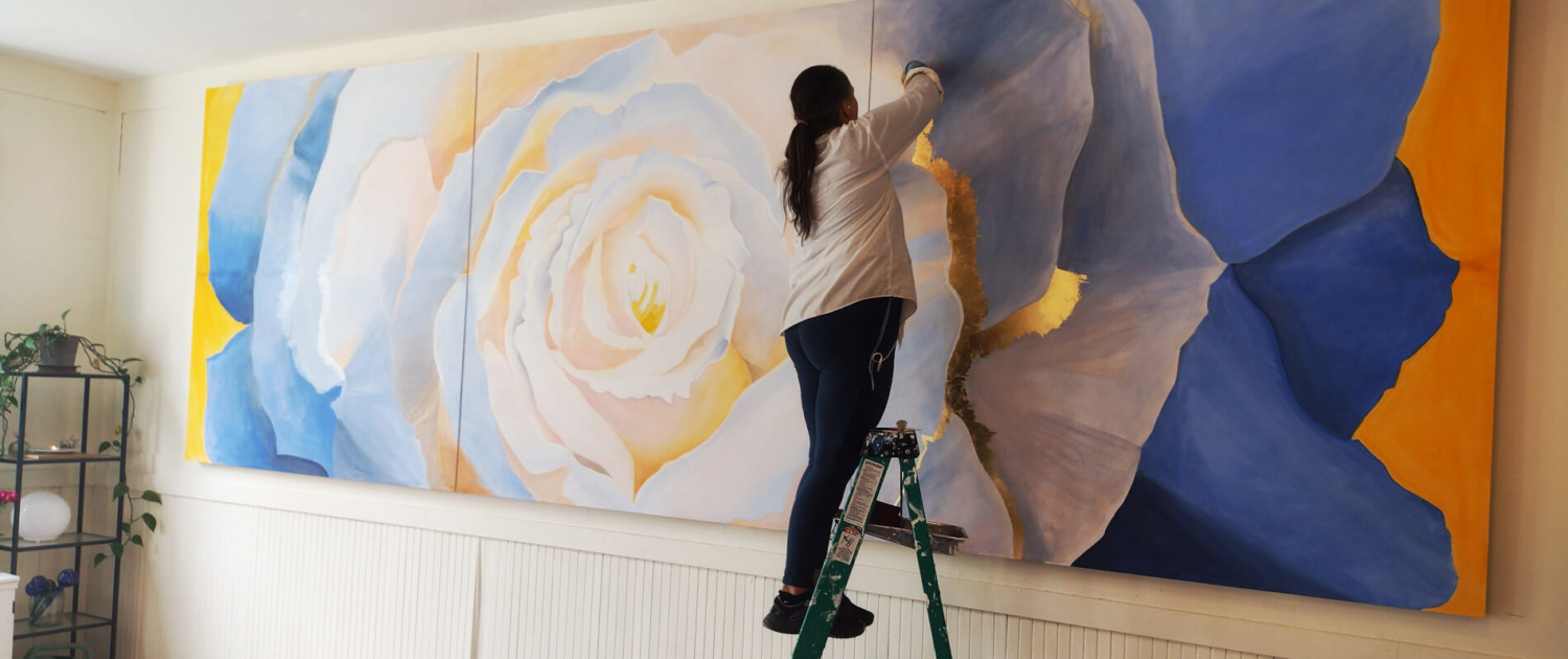 Yohanna Jessup on a ladder creating a large scale painting.