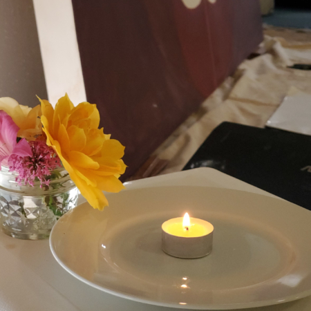 A simple painting altar with a tealight and flowers