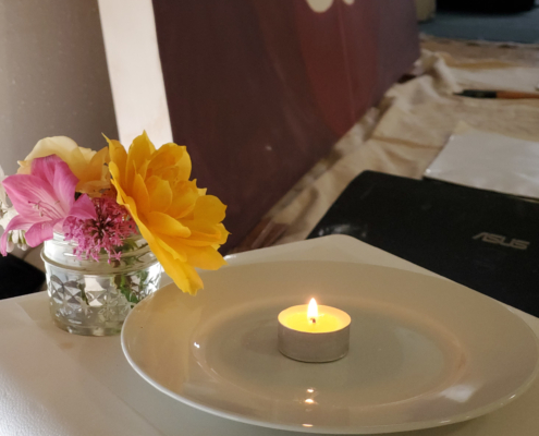 A simple painting altar with a tealight and flowers